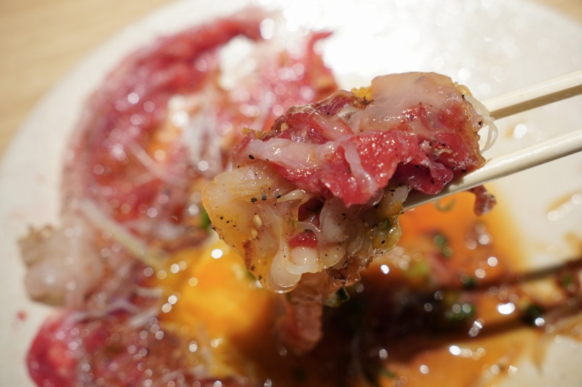 万葉牛 飲めるロースユッケのロース肉を箸で持ち上げた様子